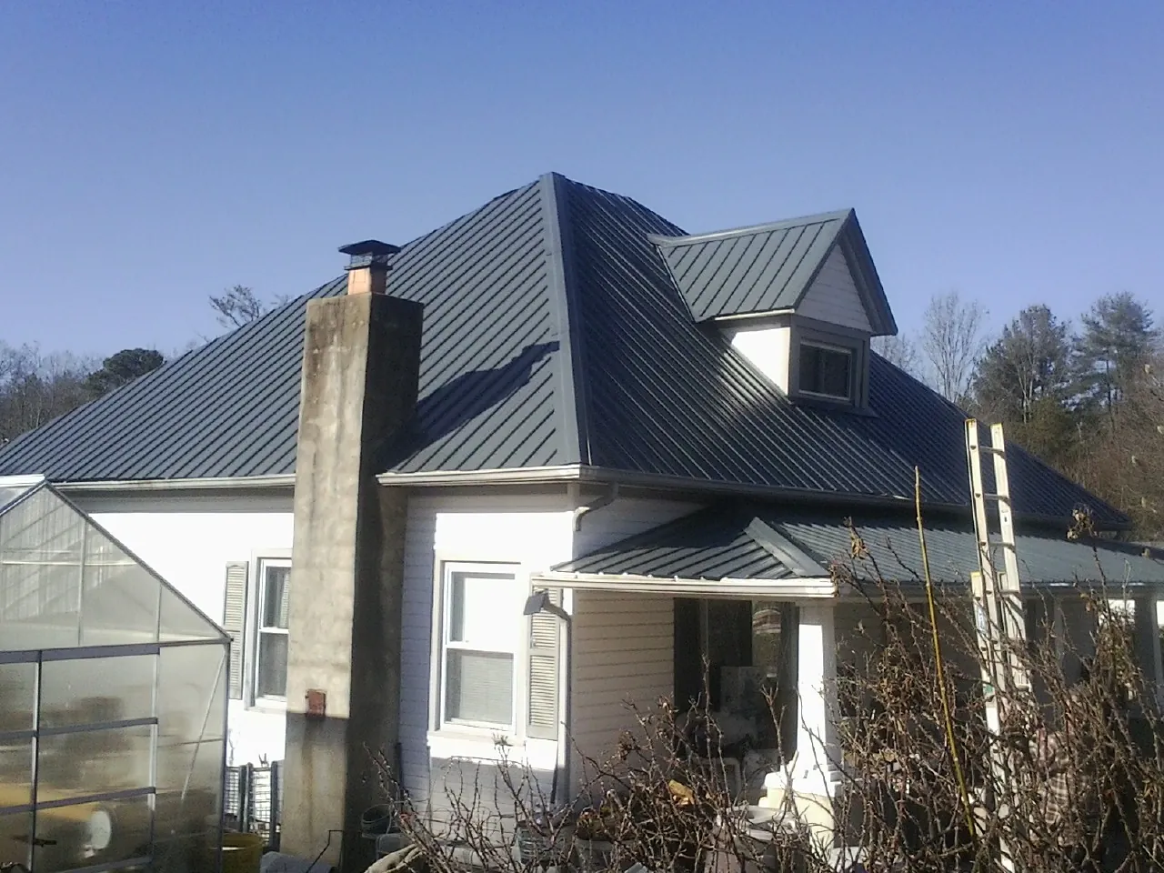 Dark blue standing seam metal roof on a white farmhouse with dormer — Slate & Tile Roof Repair by Roofing Brothers in Woodacre