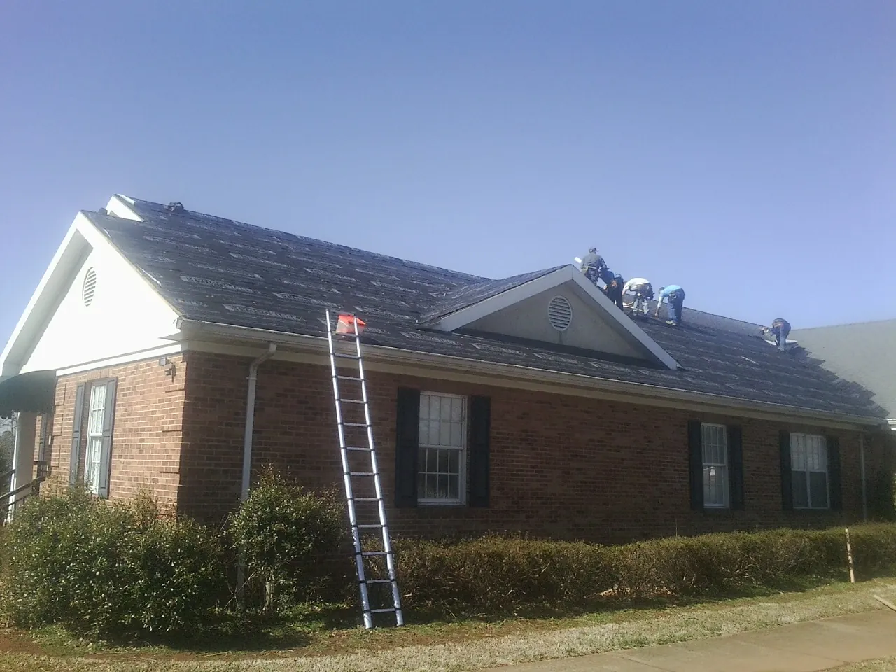 Crew tearing shingles off a brick ranch roof with a ladder set — Metal Roof Repair work by our crew in Woodacre