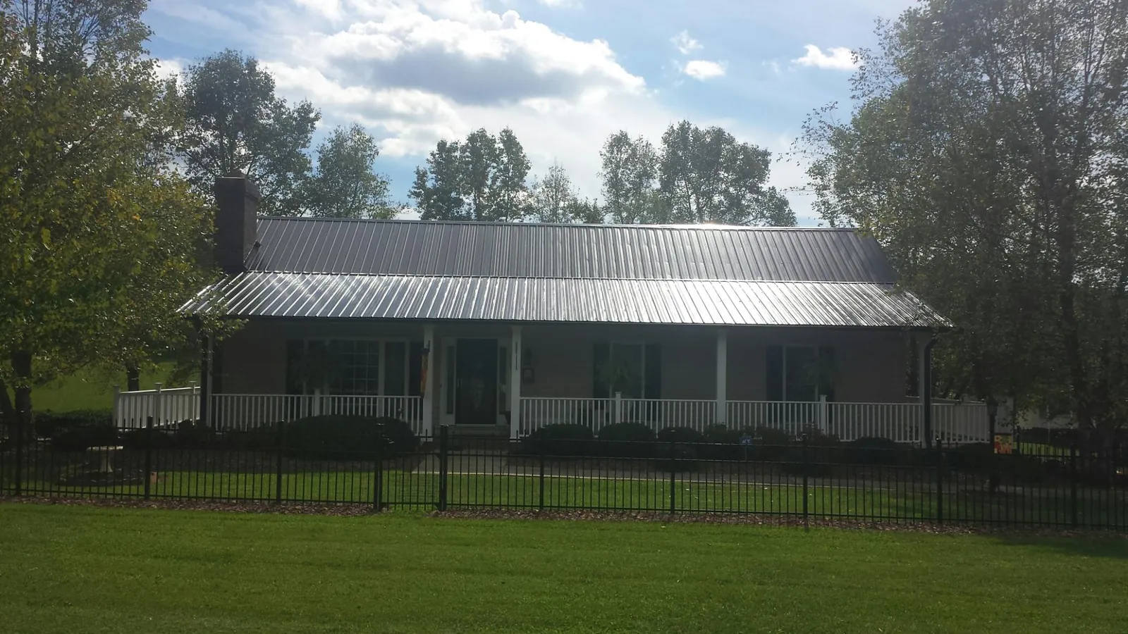Gray metal roof on a brick ranch with a full width front porch — Gutter Guard Installation work by our crew in Woodacre