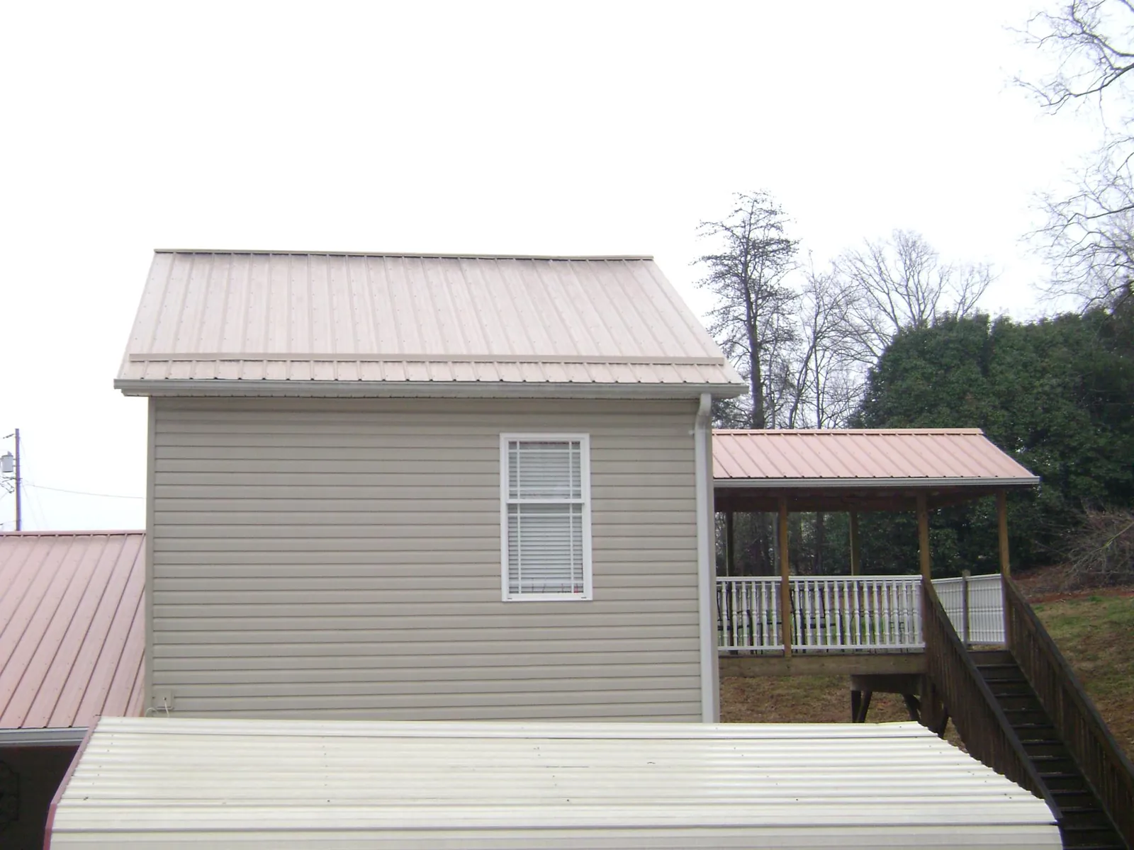 Tan metal roofs on a two story addition and attached porch, from a Roof Replacement job in Woodacre