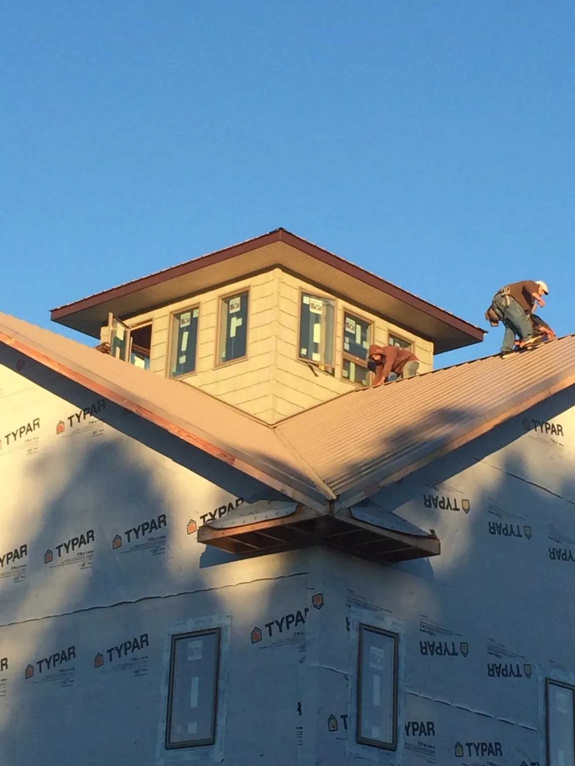 Roofers working around a rooftop cupola on a new metal roof at sunset — Roof Waterproofing in Woodacre by Roofing Brothers
